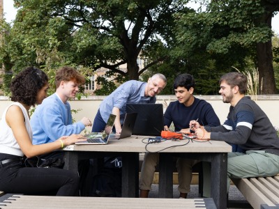 Dr Francesco Fornetti and electrical and electronic engineering students working at laptops outdoors
