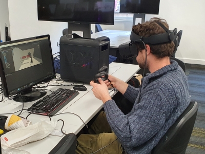 Student wearing a VR headset working on a computer game.